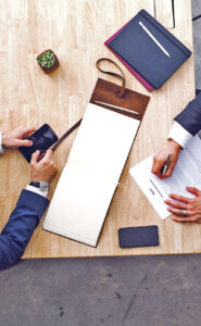 coaching20 Katja Katschemba overhead view of two professionals at a wooden table with a notebook papers a pen a smartphone and a small plant